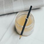 a jar of liquid with a pen on top of it