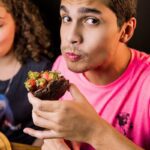 boy in pink crew neck t-shirt holding chocolate cake